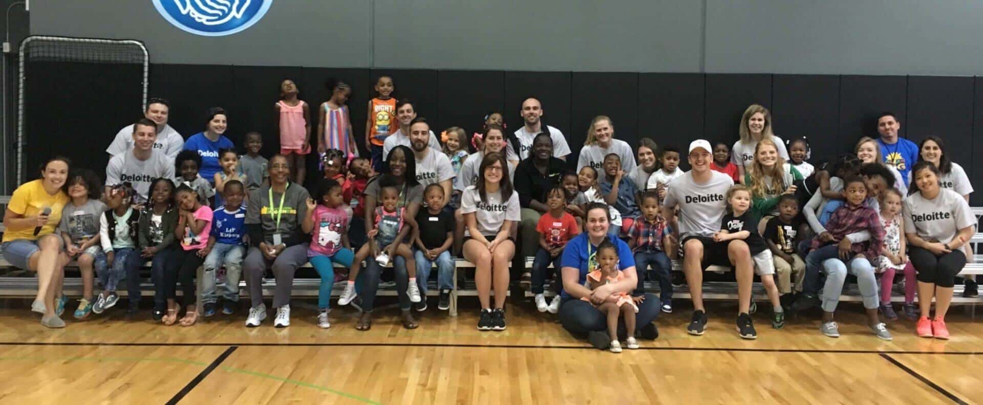 group of Deloitte volunteers sitting with children during Impact Day 2017