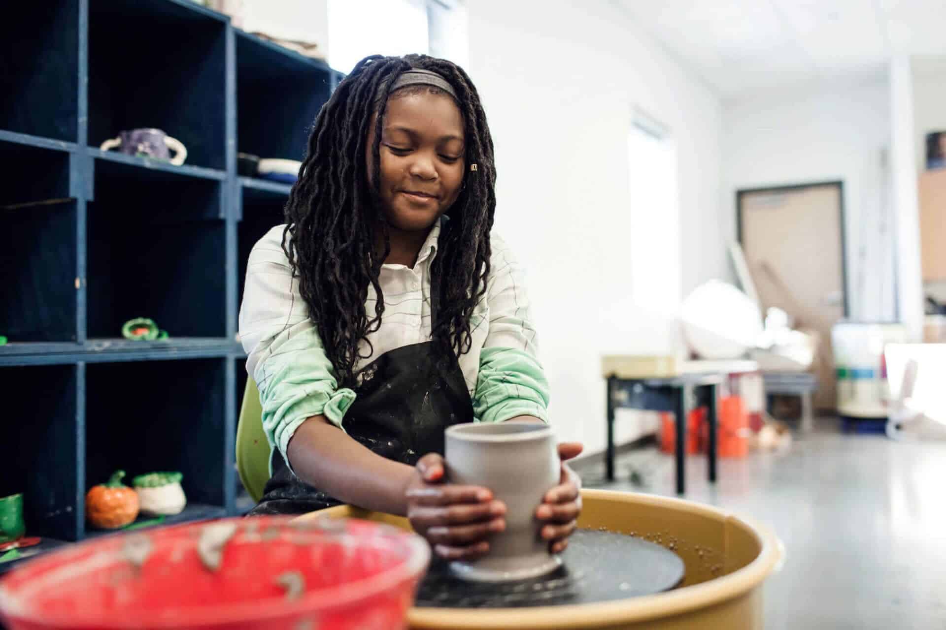 girl shaping pottery on spinning wheel