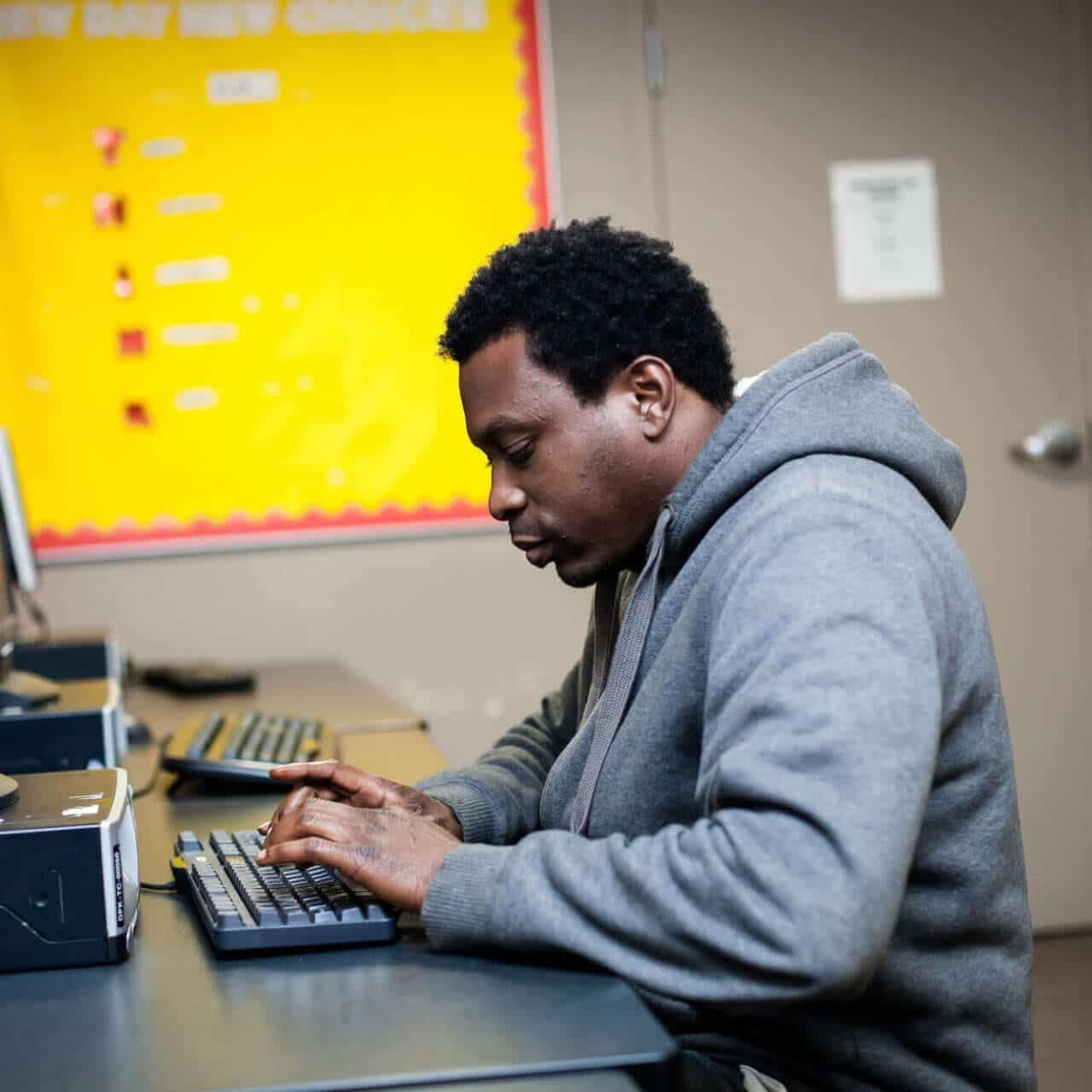 man typing on computer at Breakthrough Men's Center