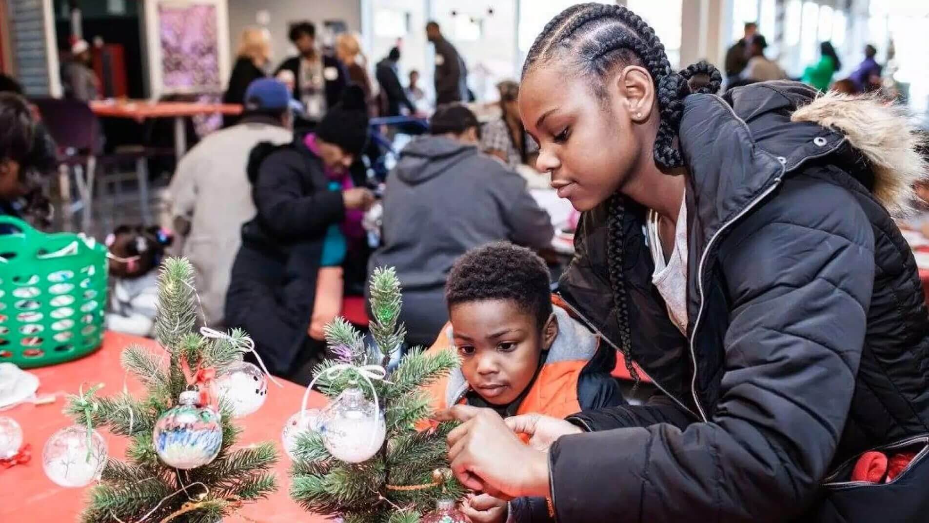 girl and young boy decorate tree at Breakthrough Christmas Store community event