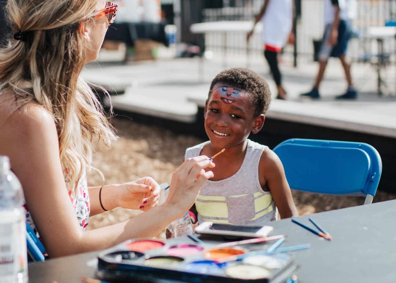 boy getting his face painted at Home Court block party in East Garfield Park